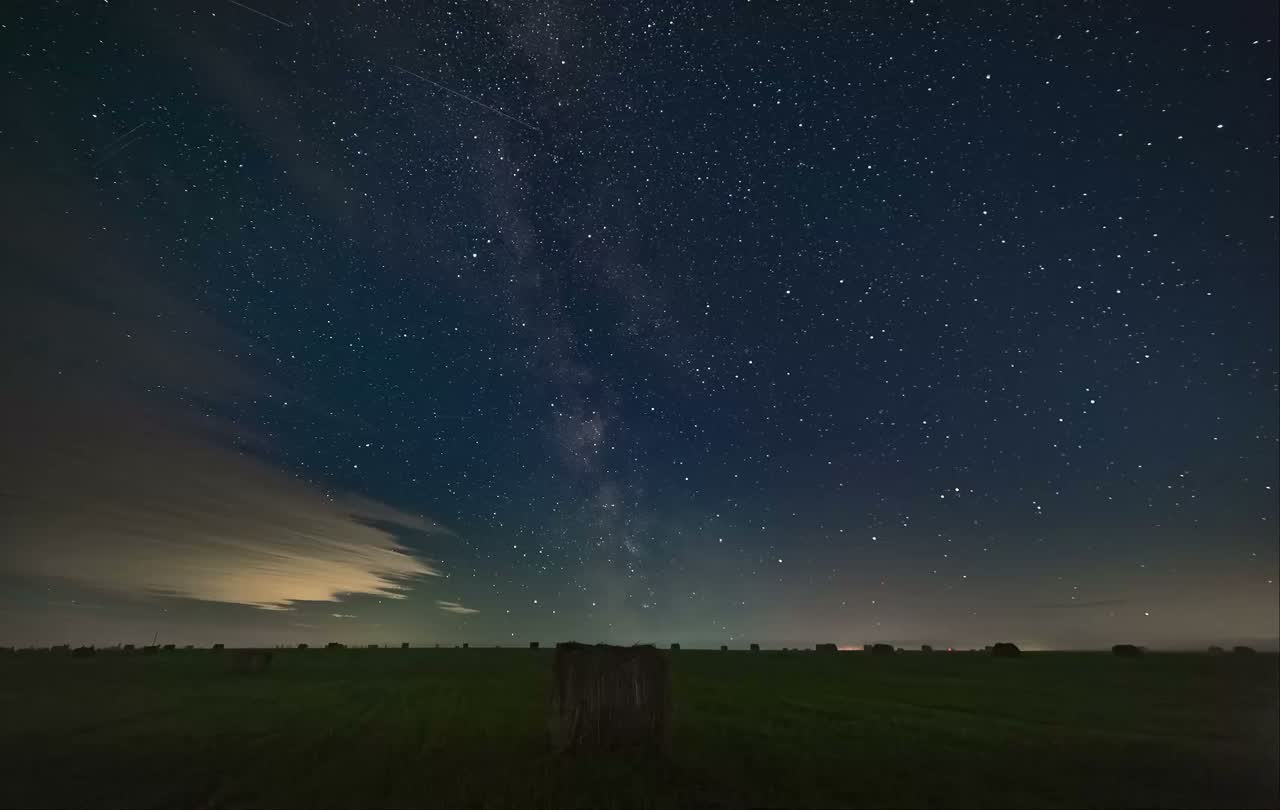 Night sky full of star trails above a communications tower